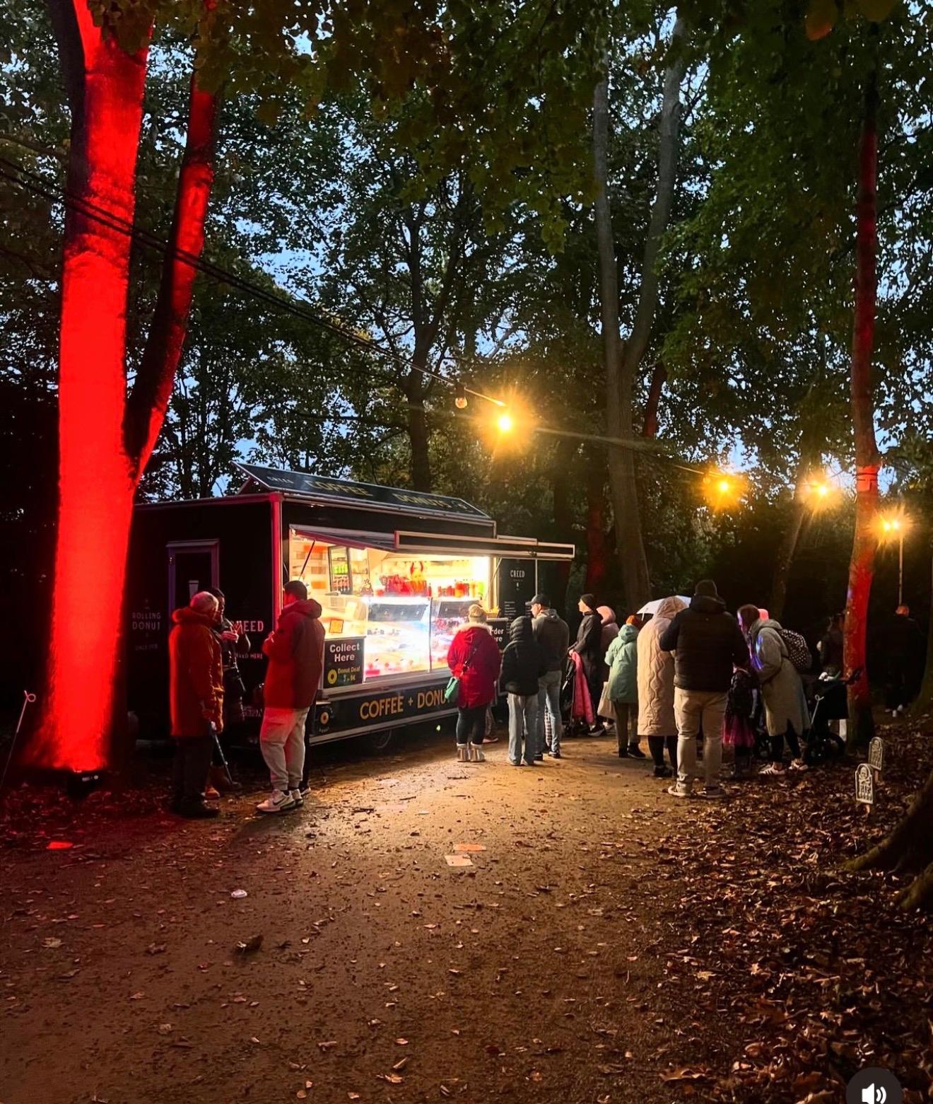 Crowd queuing at the van at a lit-up woodland night event