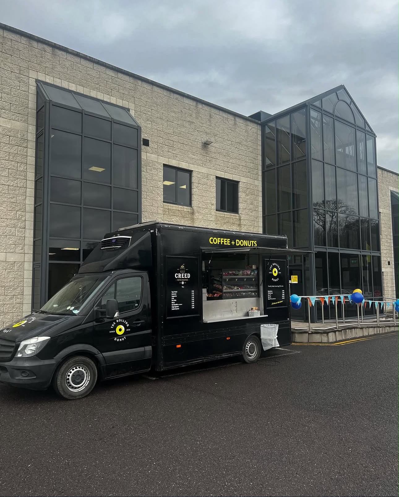 Van serving outside an office building with bunting and balloons